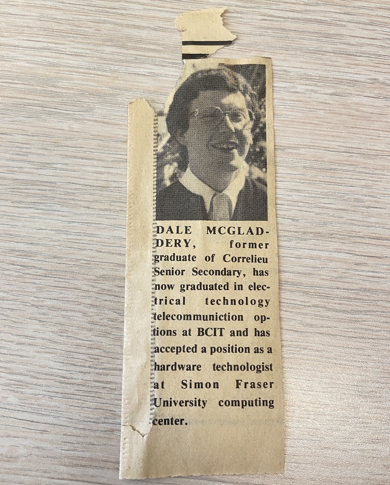 A yellowed newspaper clipping featuring a black-and-white photo of a young man in glasses and a tie, with text announcing Dale McGladdery's graduation from BCIT's electrical technology telecommunications program and his new position as a hardware technologist at Simon Fraser University's computing center.